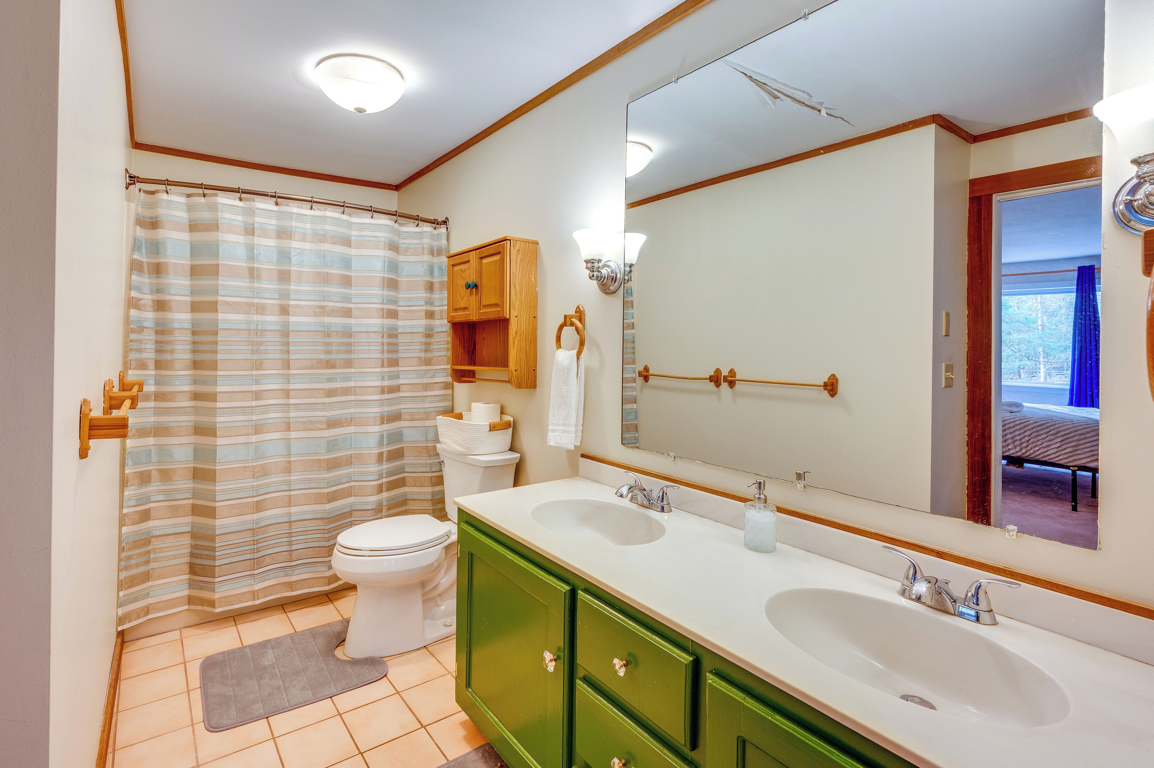 Een badkamer met douchegordijn, toilet, wastafel en kast.