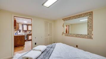 Een slaapkamer met een bed, nachtkastje, spiegel en een deur naar een badkamer.