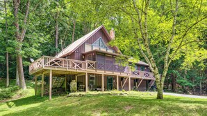 A cabin with a deck, surrounded by trees.