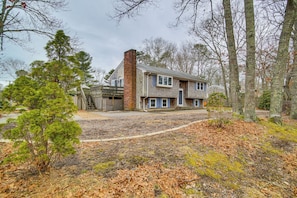 Set amidst a serene wooded area, this charming house features a balcony and a brick chimney.