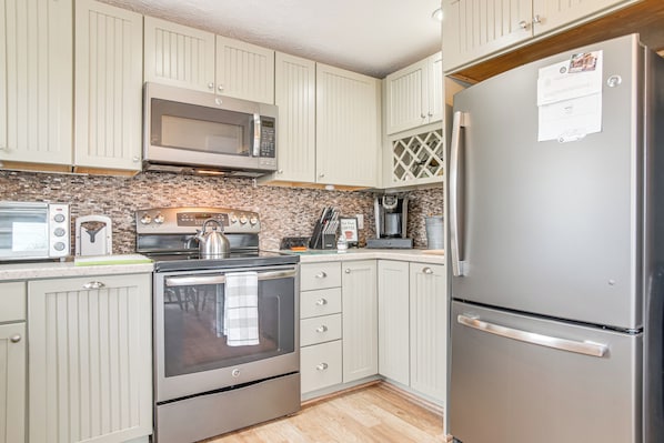 Compact kitchen area with a refrigerator, microwave, toaster, and coffee maker.