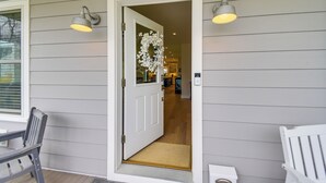 A house entrance with a white door, a bench, and a chair outside. - Walk to Beach & Central Park: Home in Cape Charles (Cape Charles)