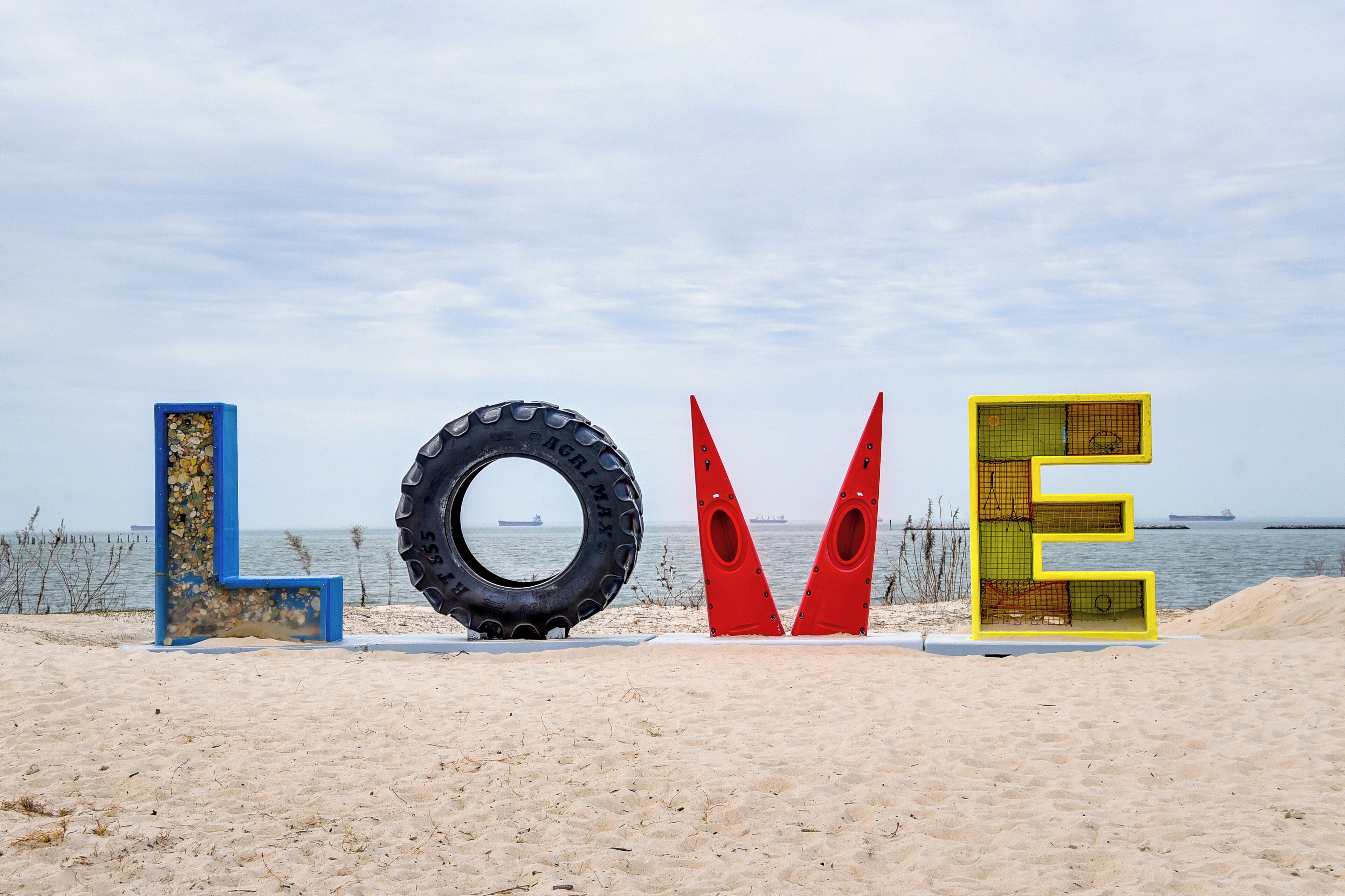 Une plage où l’on a installé de grandes lettres formant le mot « AMOUR », fabriquées à partir de pneus et d’autres matériaux.