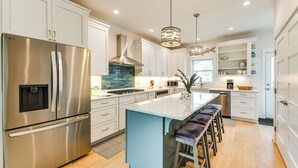 A modern kitchen with stainless steel appliances, a central island with bar stools, and pendant lighting. - Walk to Beach & Central Park: Home in Cape Charles (Cape Charles)