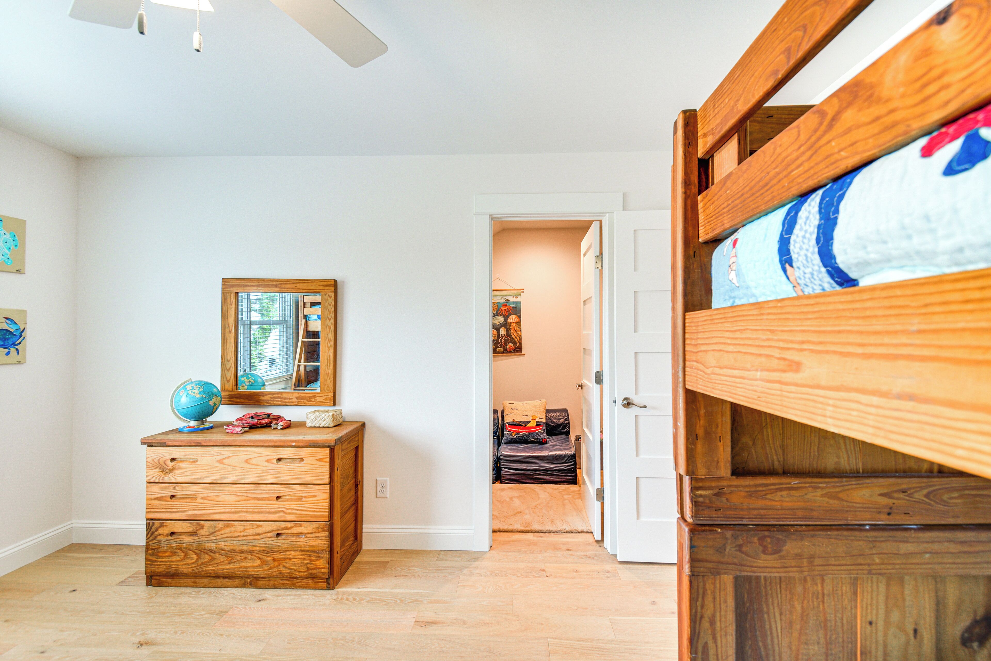 Una habitación con un aparador de madera, un espejo y una cama litera.