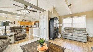 A spacious living room with a ceiling fan, a fireplace, and a view of the kitchen. - Water-view Deck: Home on Dale Hollow Lake (Albany)
