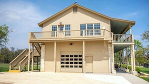 A two-story house with a covered front porch, a garage, and a staircase leading to the upper level. - King Beds, Game Room, On 290, Large Estate,Kitchen (Fredericksburg)