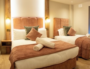 Une chambre d’hôtel avec deux lits, chacun doté d’une tête de lit, de tables de chevet et de lampes.