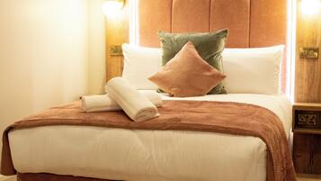 A neatly made bed with a brown headboard, white linens, and two pillows. There are two wall-mounted lights on either side of the bed.