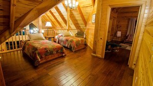 A cozy attic bedroom with two beds, wooden beams, and a view of the outside. - Talako Lodge|4+BD|4BTH|16 Guest|Hot Tub|3 Story|Pool table (Broken Bow)