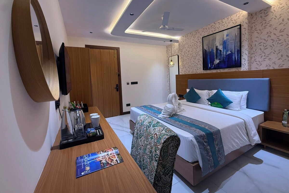 Ein Hotelzimmer mit Bett, Nachttisch, Schreibtisch und einem großen Spiegel.