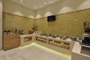 Un área de bufé con salpicadero de azulejos, un televisor de pantalla plana y diverso equipo para el servicio de alimentos.