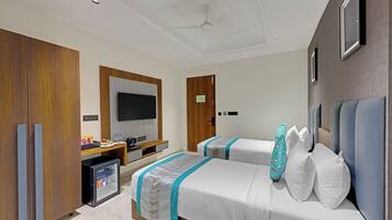 A hotel room with two beds, a TV, a minibar, and wooden cabinets.