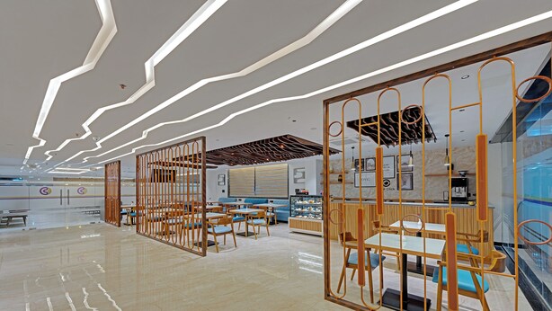 A modern interior with a sleek, polished floor, contemporary furniture, and a distinctive ceiling design with linear light fixtures.