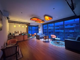 Un interior moderno con una zona de bar, asientos y ventanas amplias con vistas a la ciudad.
