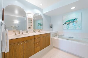 A modern bathroom with two sinks, a bathtub, wooden cabinets, and a large mirror. - Vista Waikoloa G203: Luxury Condo in Waikoloa Resort: AC, Elevators, Views! (Waikoloa)