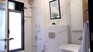 Un baño moderno con una bañera independiente, un espejo grande y un inodoro.