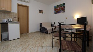 Una cucina compatta con macchina del caffè, un piccolo frigorifero e un'area pranzo con tavolo e sedie.