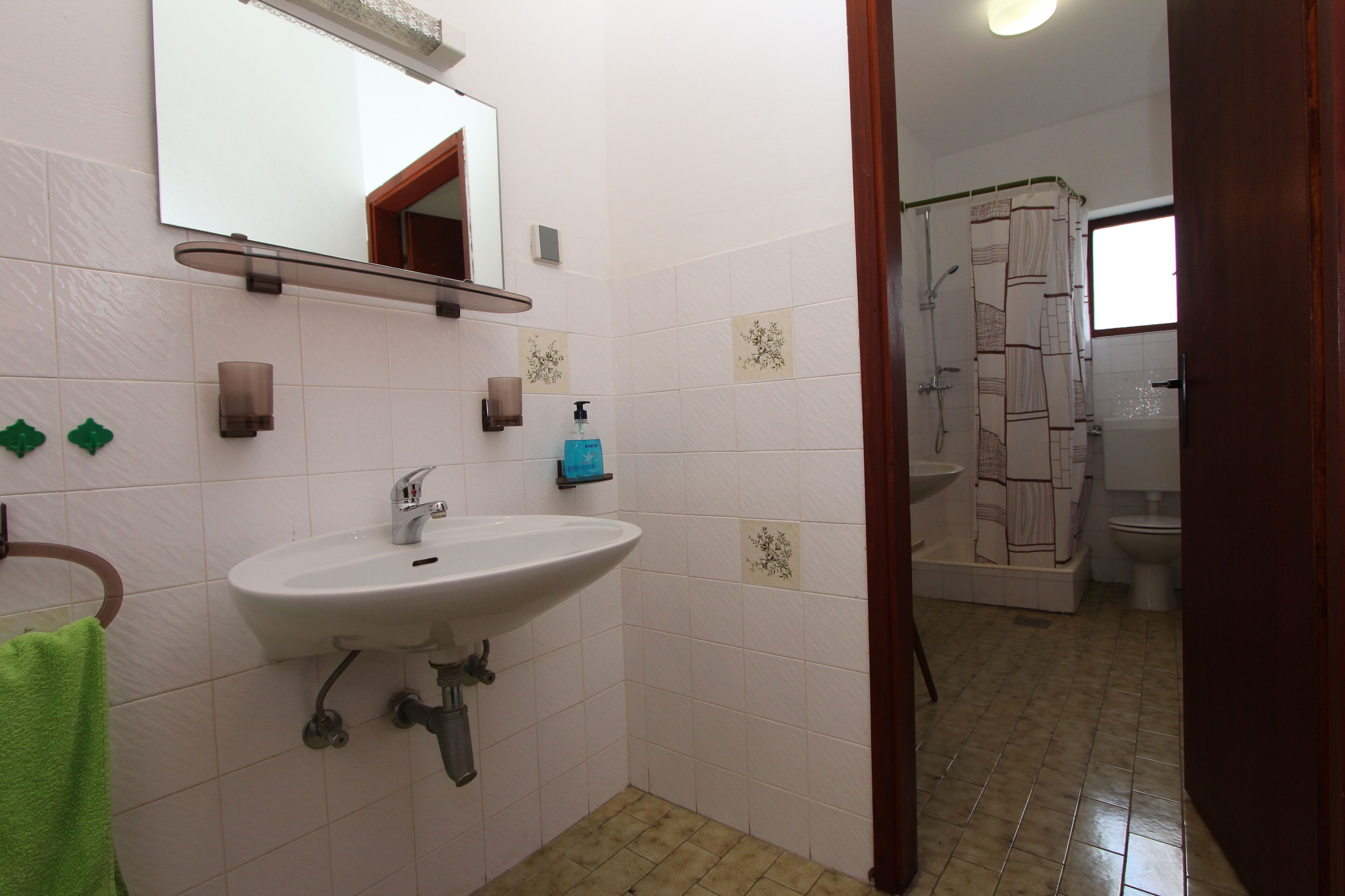 A bathroom with a sink, mirror, shower, and toilet.