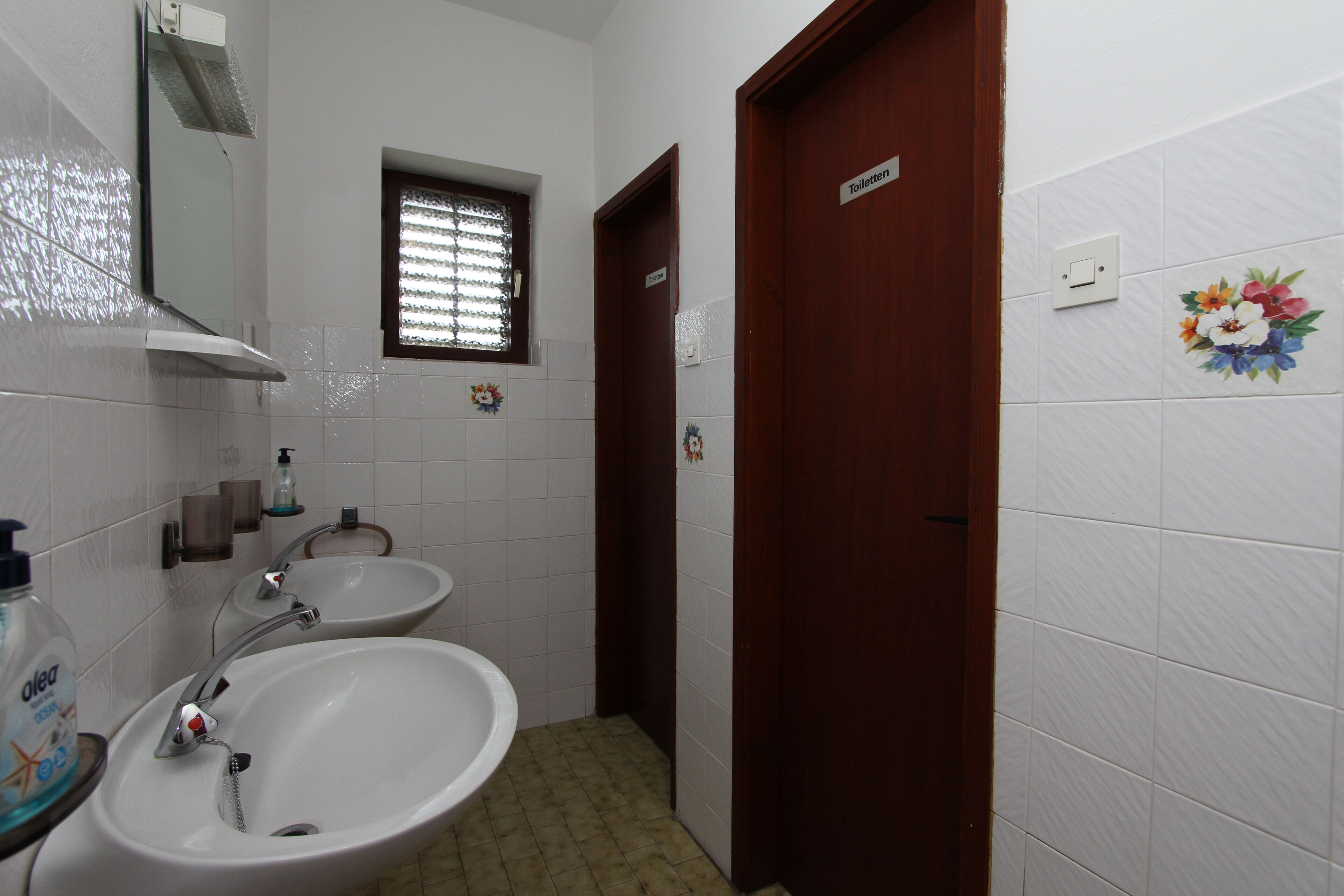 A bathroom with two sinks, a mirror, a window, and a door.