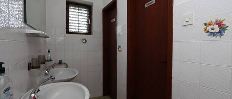 A bathroom with two sinks, a mirror, a window, and a door.