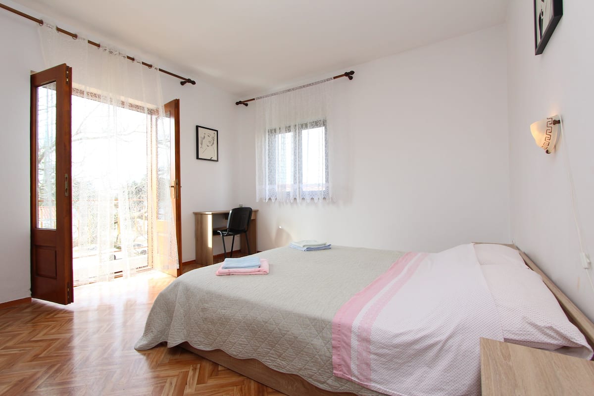 A bedroom with a bed, a desk, and a chair.