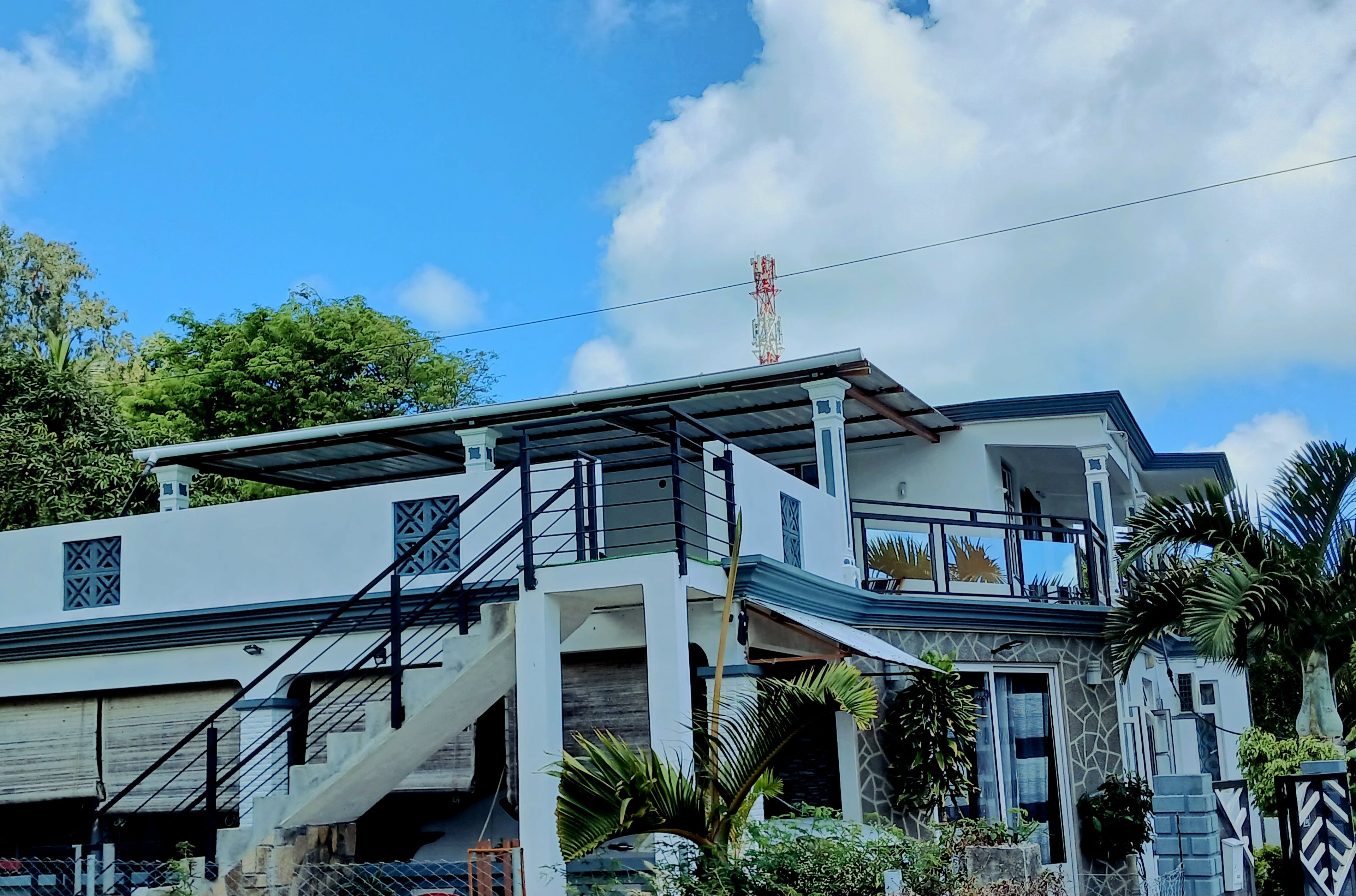 Une maison moderne à deux étages, dotée d’un espace extérieur couvert, d’un escalier et d’une antenne parabolique.