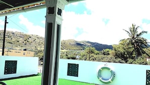 A view from a covered outdoor area with a white column, green artificial turf, and a lifebuoy on a light blue wall. - ENTRE VALLEE (Rodrigues Island)