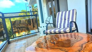 A balcony with a wooden table and striped chair, overlooking a lush landscape. - ENTRE VALLEE (Rodrigues Island)
