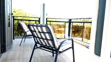 Een balkon met twee streepstoelen en een tafel.