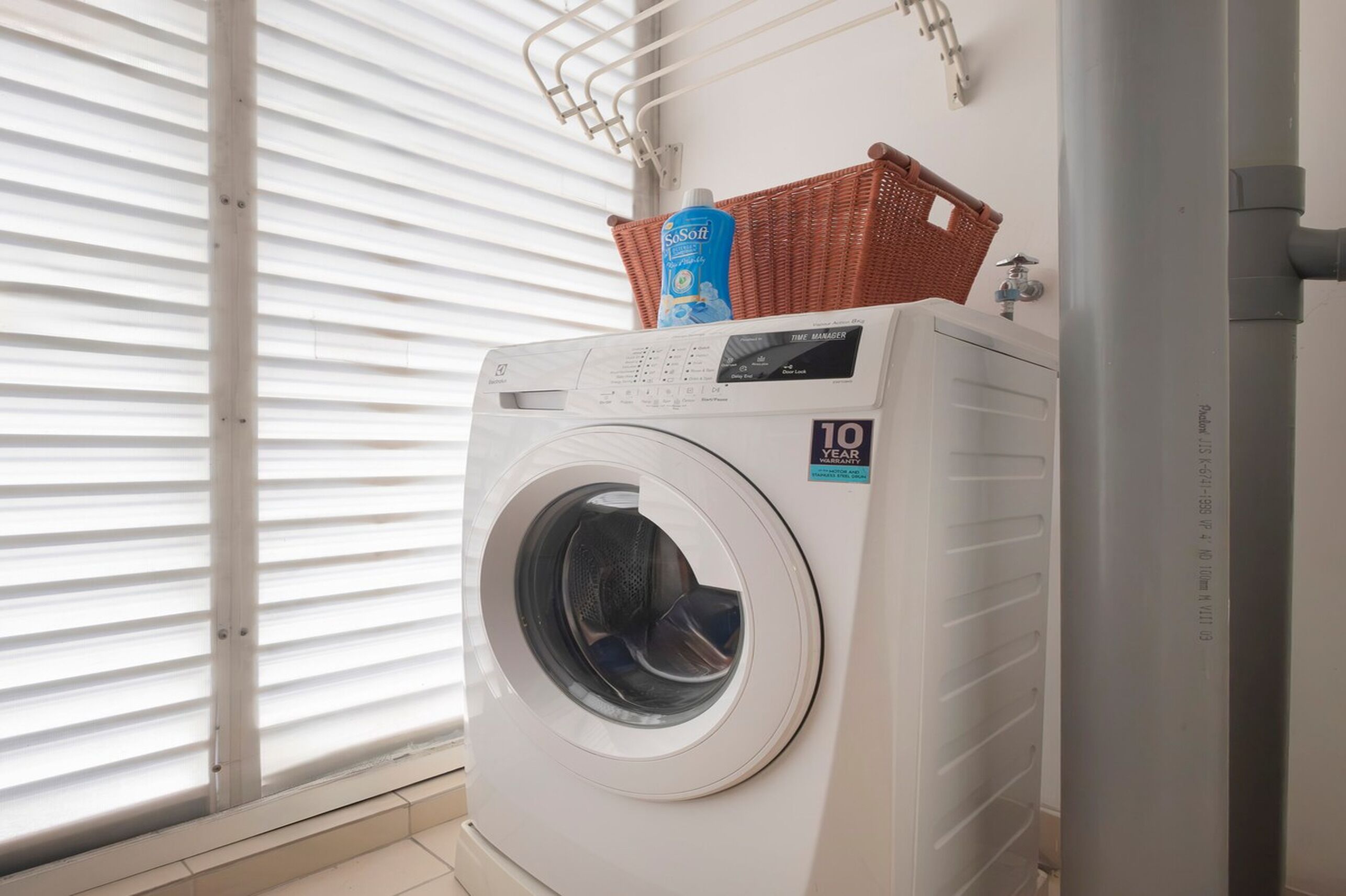 Un lave-linge à chargement frontal doté d’un panneau de commande, d’un panier contenant de la lessive et d’une fenêtre avec des stores.