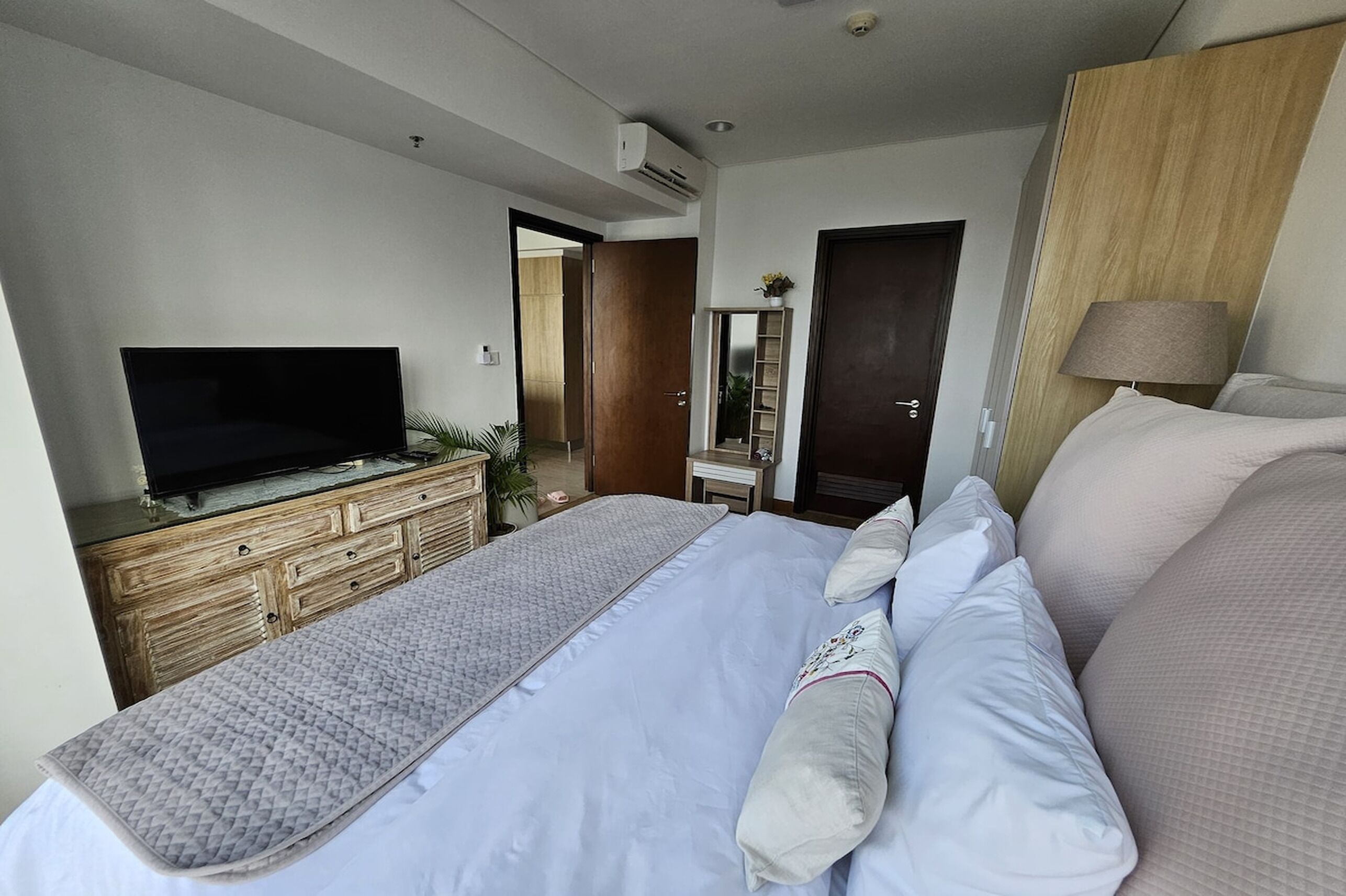 Ein Hotelzimmer mit Bett, Fernseher, Kommode und Spiegel.