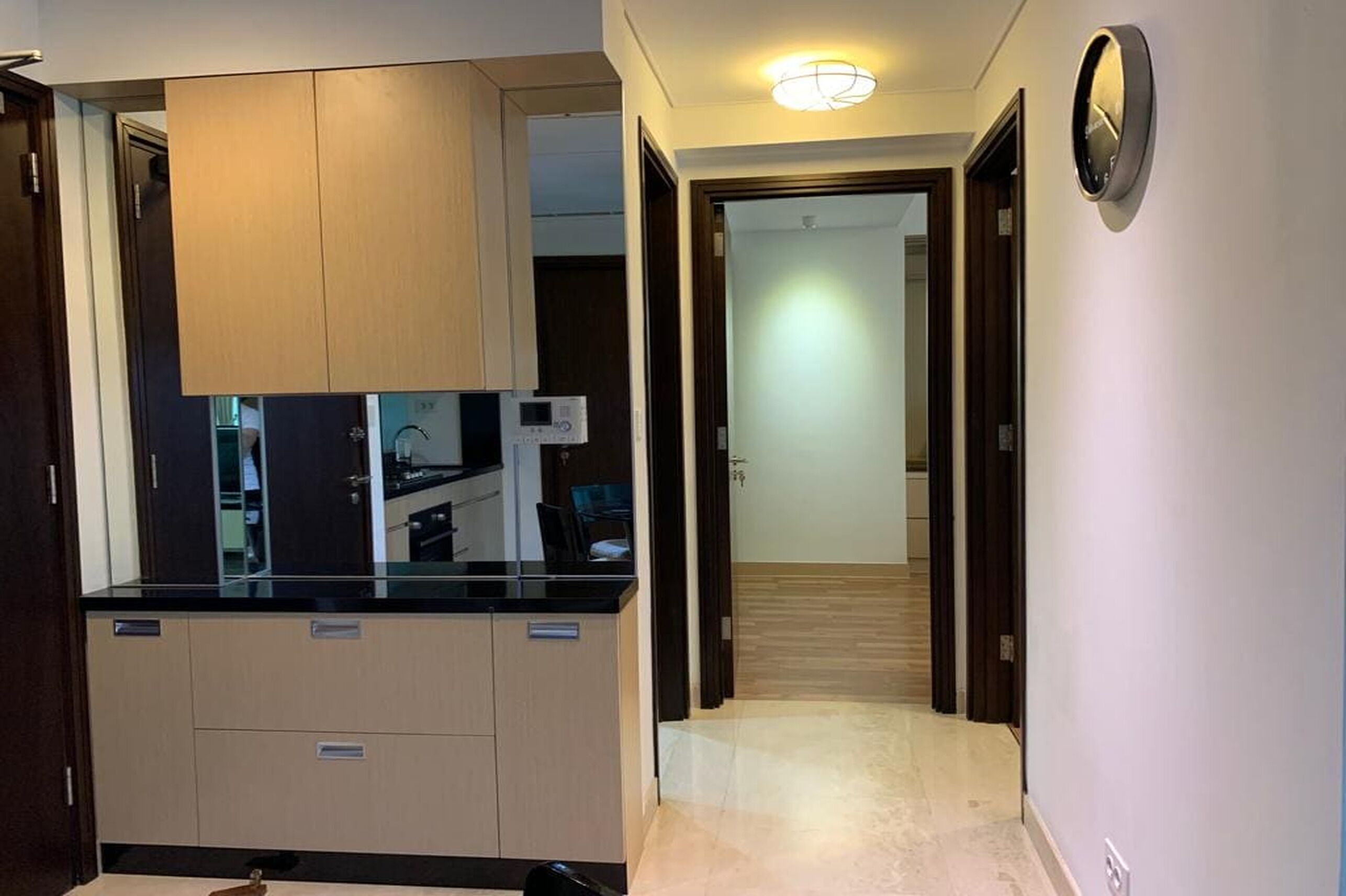 A hallway with a kitchen area featuring cabinets and a countertop.