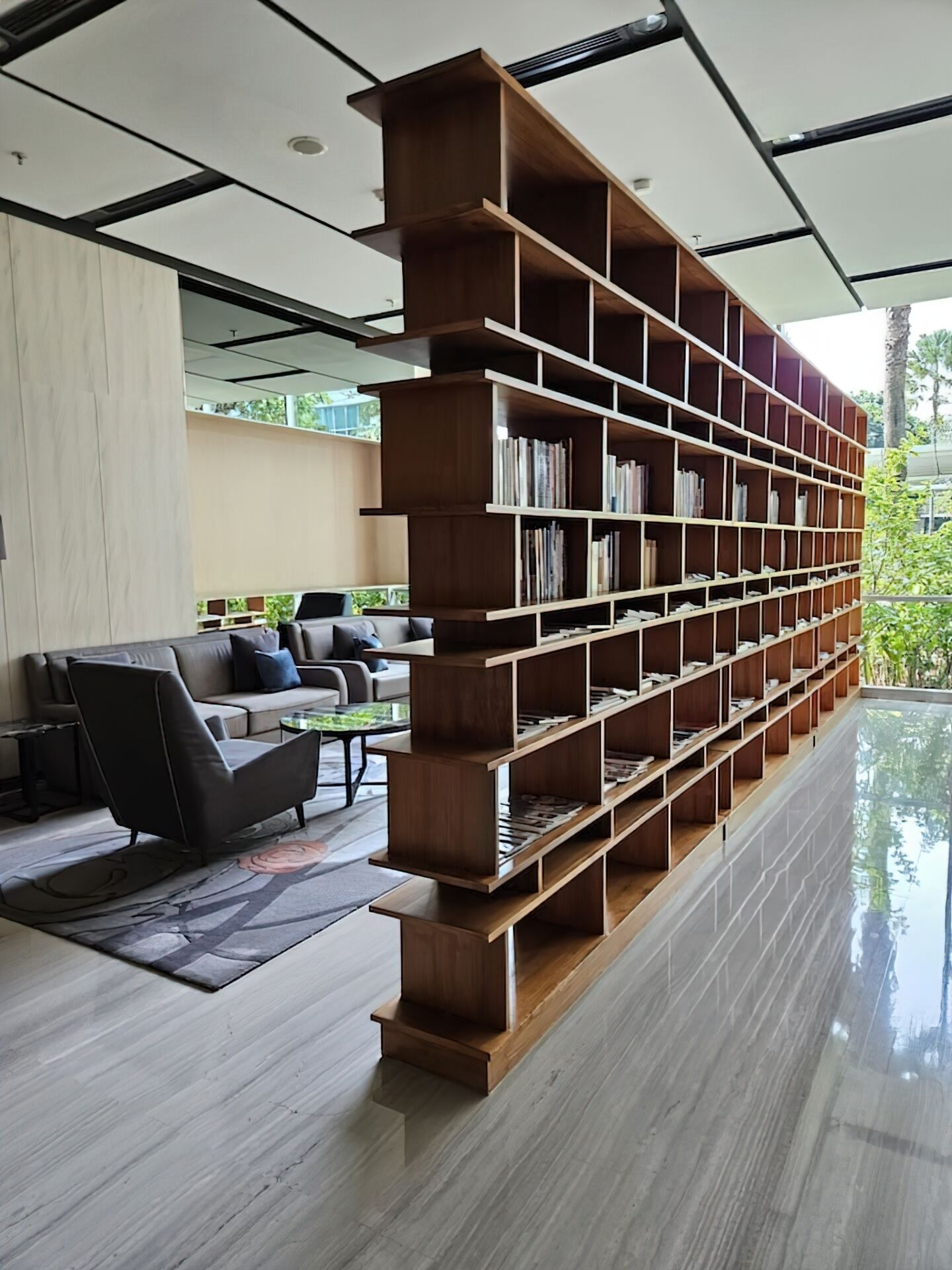 Ein modernes Wohnzimmer mit einem großen Bücherregal aus Holz, einer Ledersofa und einem Glastisch.