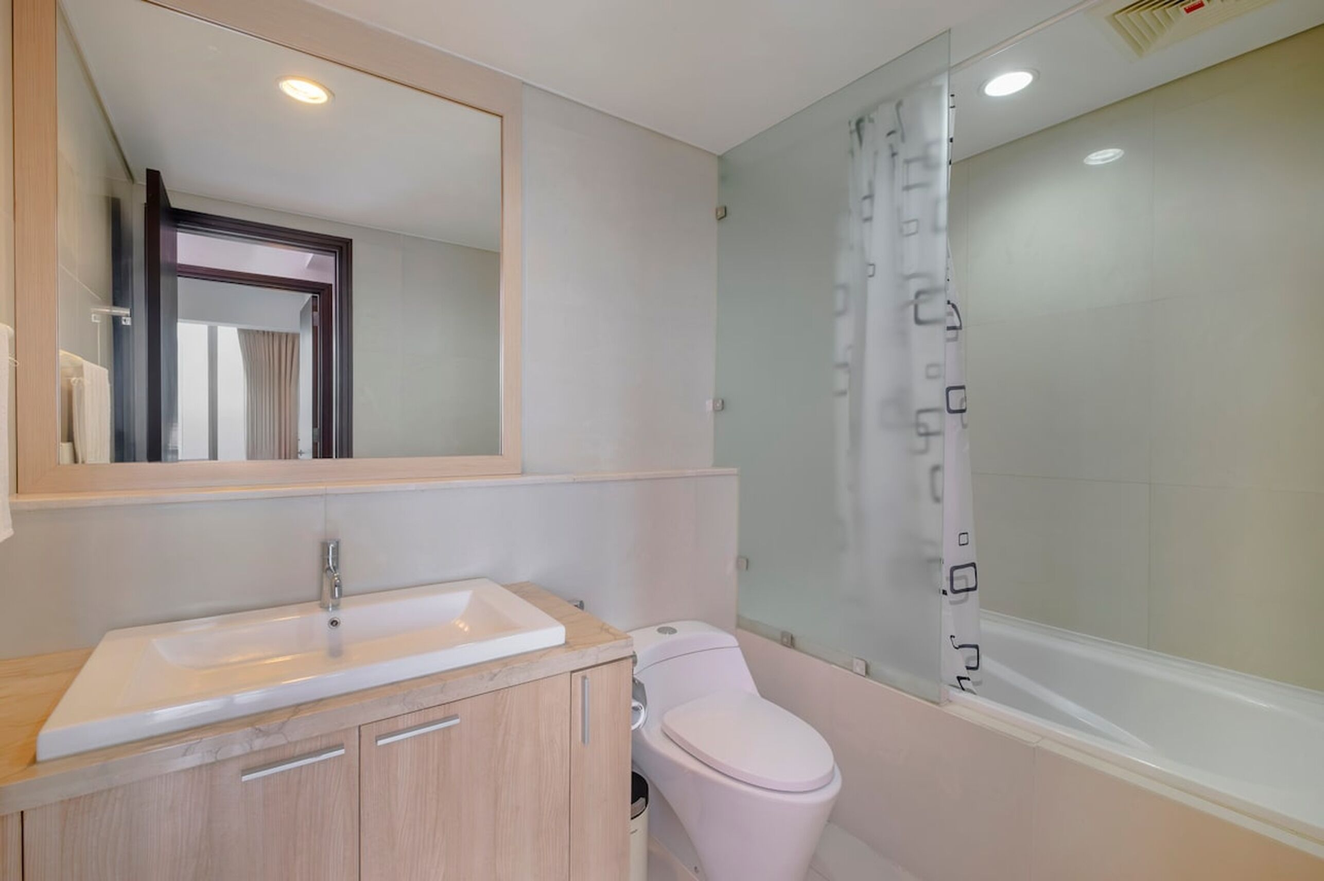 A modern bathroom with a sink, toilet, and glass shower enclosure.