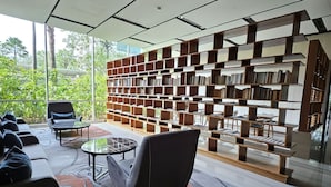 Een moderne bibliotheek met een grote boekenkast, comfortabele zitplaatsen en uitzicht op groen.