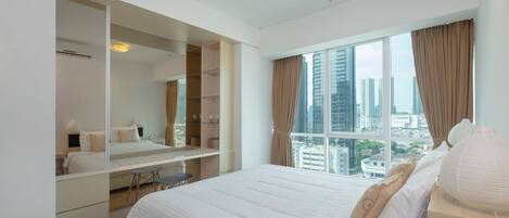 A modern hotel room with a large bed, a walk-in closet, and a city view.