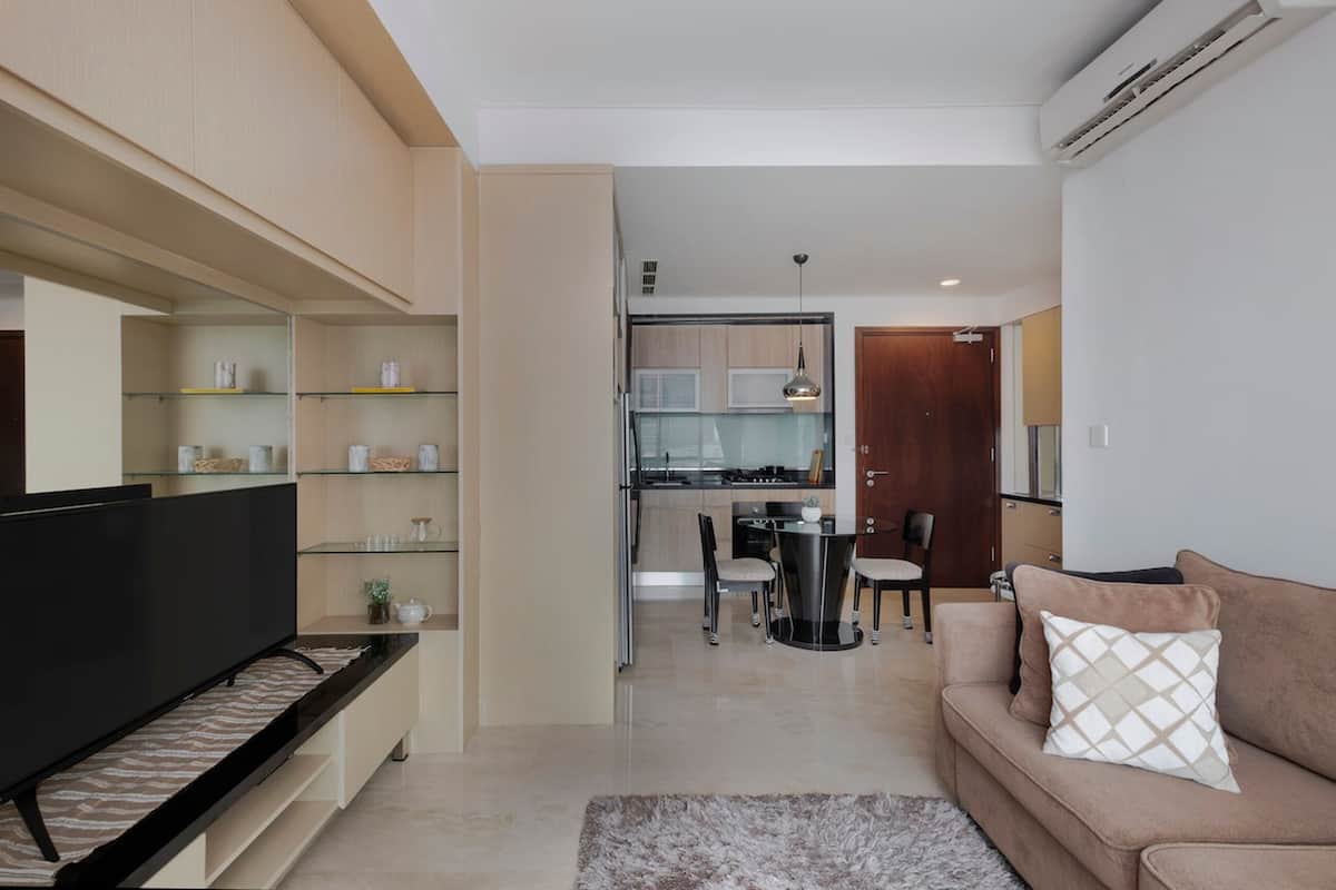 A modern living room with a flat-screen TV, a sofa, and a dining area with chairs.