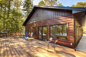 Een chalet met een terras, grote ramen en uitzicht op het bos.