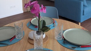 Une cuisine moderne avec des meubles blancs, un réfrigérateur bleu clair et un coin repas avec une table en bois, mise pour quatre personnes.