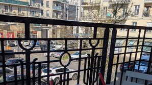 Une table avec deux tasses et une assiette de croissants, placée sur un balcon d’où l’on peut admirer les voitures garées et les bâtiments.