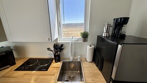 Een moderne keuken met een fornuis, spoelbak en koffiezetapparaat.