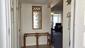 Un couloir avec un lampadaire à pied en bambou, un miroir et une porte dotée d’un verrou à chaîne.