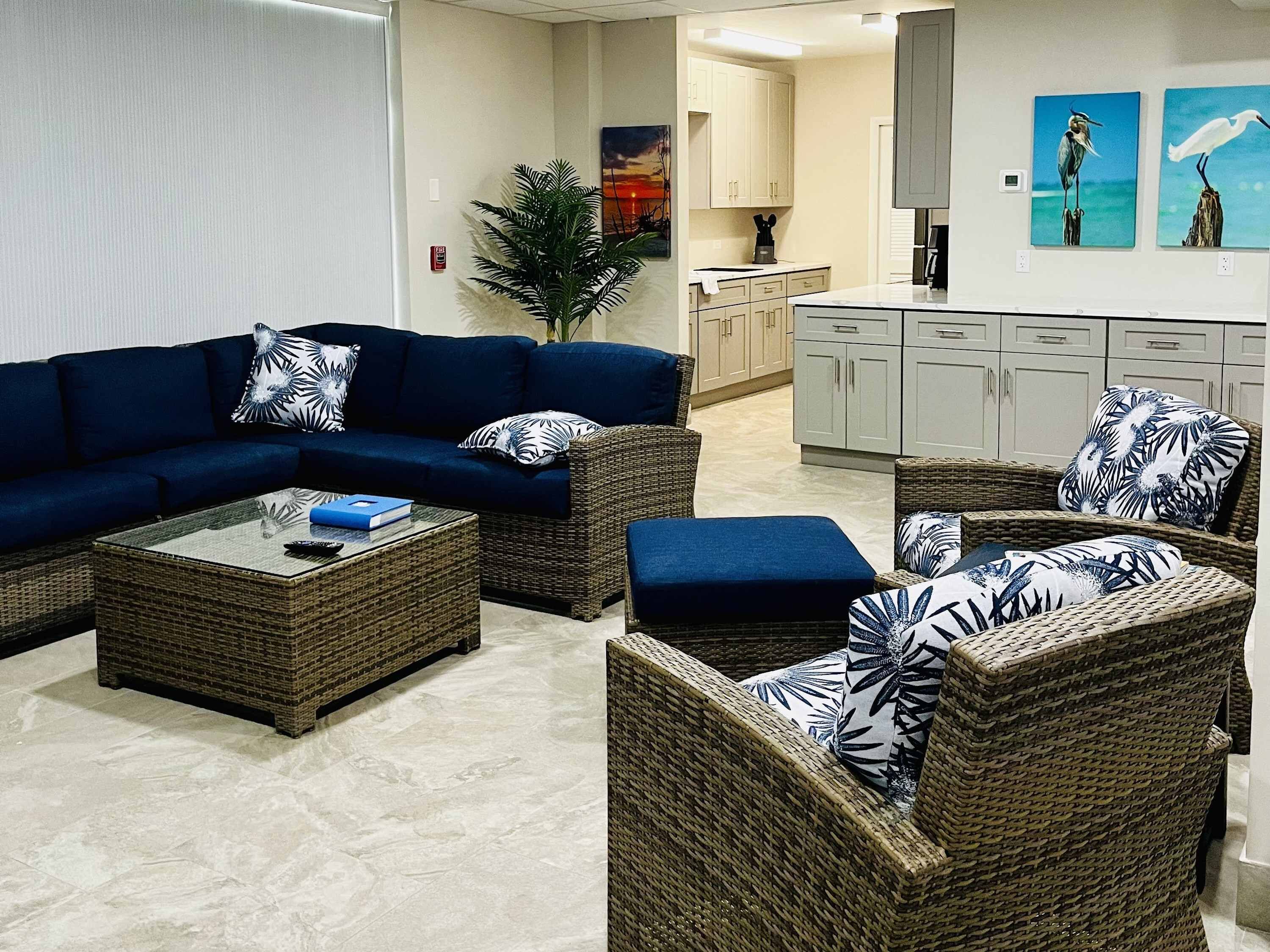 A living room with a sectional sofa, two armchairs, a coffee table, and a potted plant.