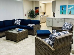 A living room with a sectional sofa, two armchairs, a coffee table, and a potted plant.