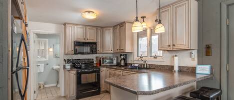 A kitchen with a central island, built-in appliances, and pendant lighting.