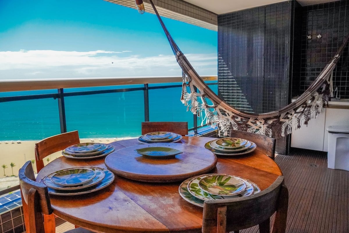 A round wooden table with plates and a hammock.