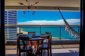 A balcony with a view of the ocean, a hammock, and a table with chairs. - Beira Mar Fortaleza Landscape Platinum  (Fortaleza)