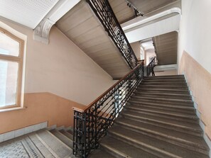 A staircase with ornate black railings, a patterned floor, and a plain wall. - City View Apartment SOHO (Budapest)