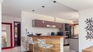 A modern kitchen with a wooden island, bar stools, and stainless steel appliances. - Bz40 Casa 180m praia piscina privativa (Buzios)